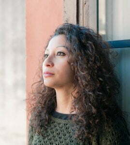 A woman with curly hair enjoying the view from a window in an outpatient program.