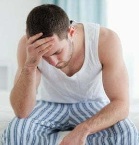 A man sitting on bed at a men's only rehab center