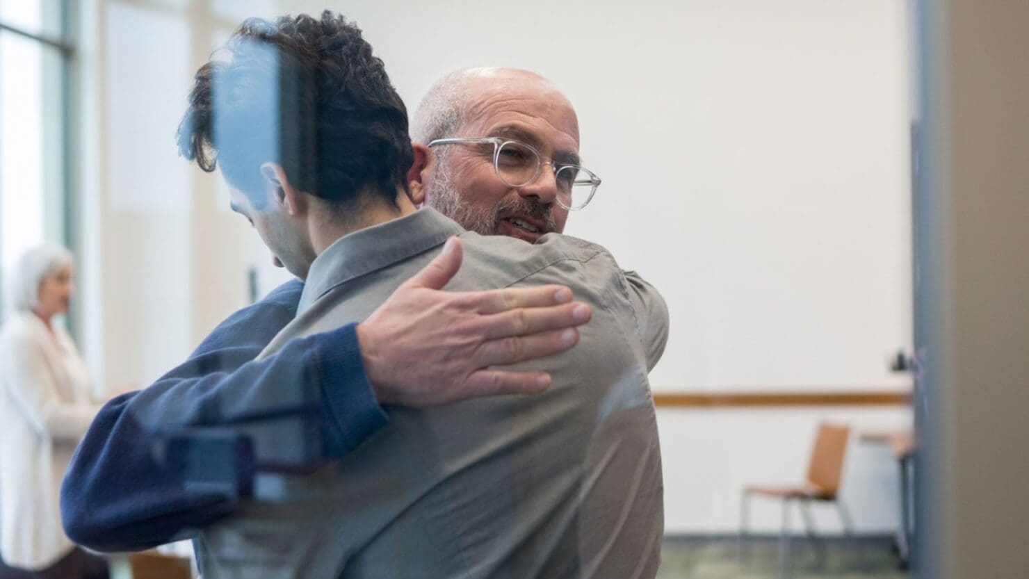 A man is hugging another man in a rehab center courtroom.