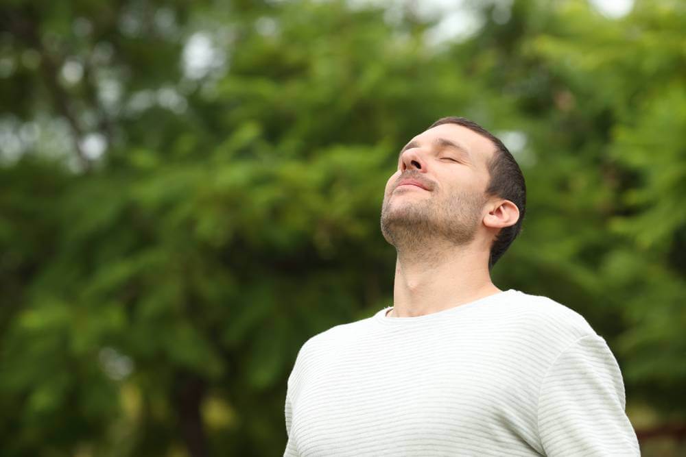 A man peaceful with his eyes closed is meditating in a park, seeking inner peace and tranquility.